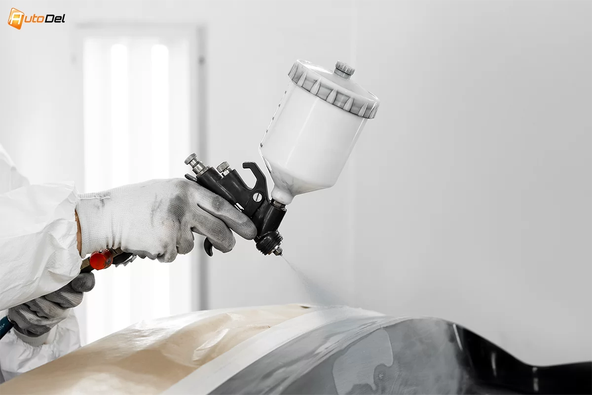 persoana cu un pictol de aer, ce vopseste o masina